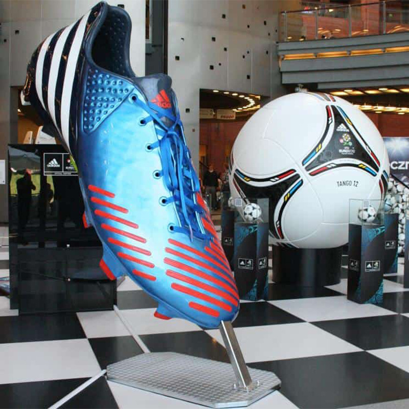 Large display of a blue and red Adidas soccer cleat and a giant Adidas Tango 12 soccer ball.