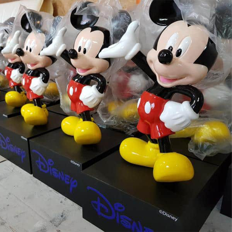 Several Mickey Mouse figurines lined up, each wearing a plastic cover and standing on black bases with the Disney logo.