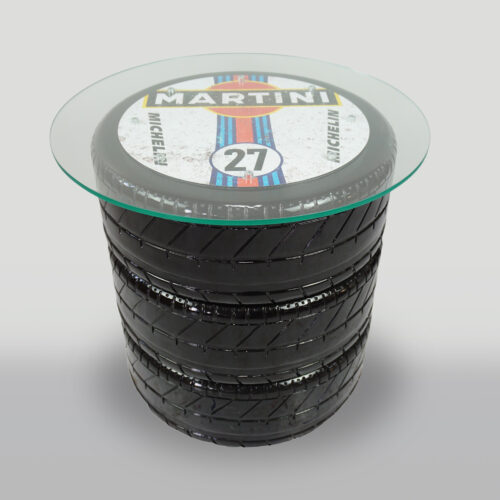 A coffee table made from stacked black car tires, topped with a round glass surface displaying a 