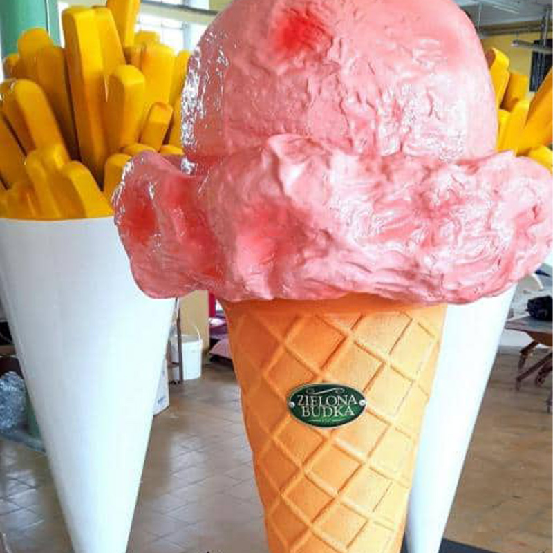 Large plastic models of a yellow ice cream cone with a pink scoop and a white cup filled with yellow fries on display.