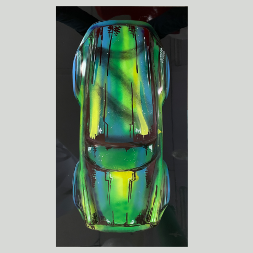 Colorful miniature car model with a vivid, abstract green, blue, and yellow paint design.