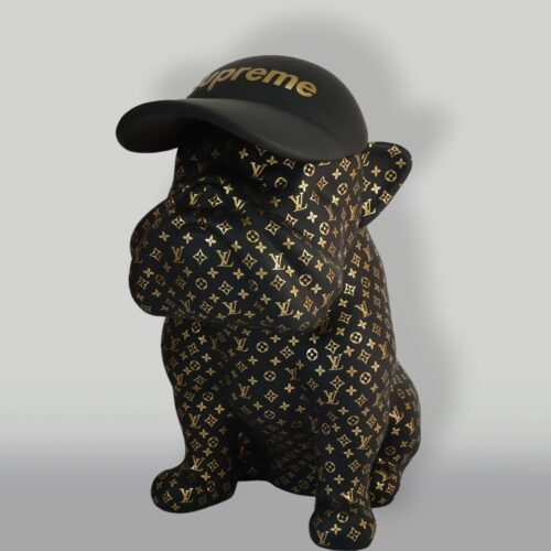 A black French Bulldog statue covered in Louis Vuitton monogram print and wearing a Supreme hat.