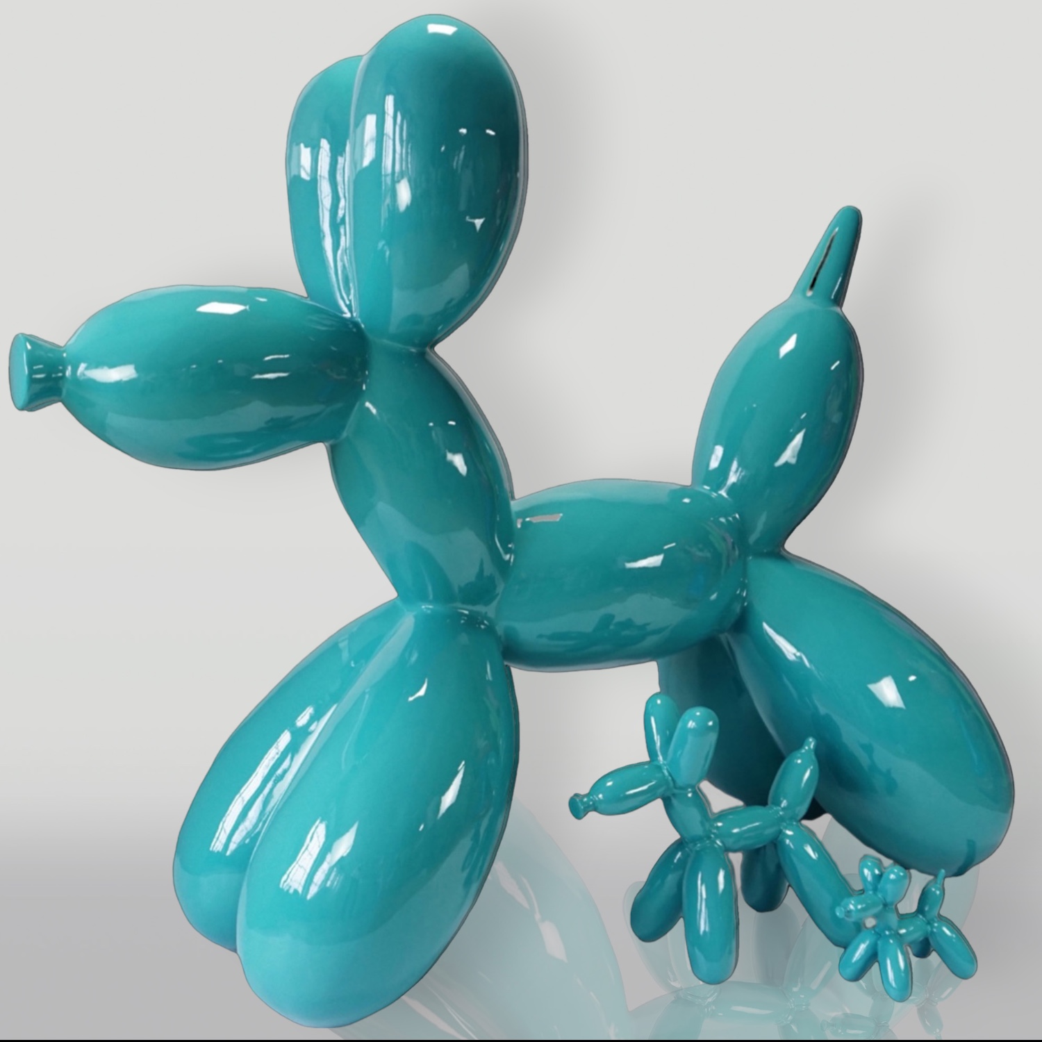 Balloon Dog Small Decorative Figure - Turquoise 3 A teal-colored, balloon-animal sculpture resembling a dog with a smaller balloon-animal sculpture of the same design and color in front of it.