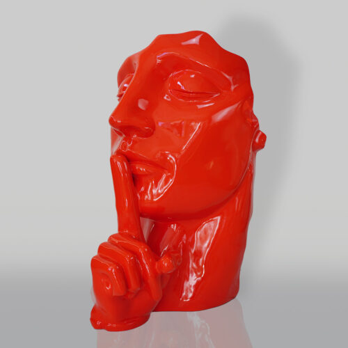 Red glossy sculpture of a human face with a finger on its lips in a shushing gesture.