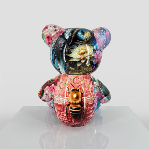 A colorful teddy bear figurine featuring floral designs, a dragonfly with the word
