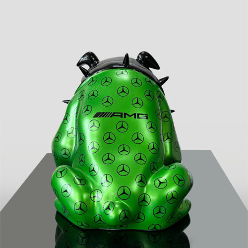 Green sculpture with a frog shape, covered in black Mercedes-Benz logos and the AMG emblem, featuring black spikes on its back.