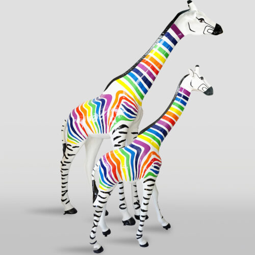 Two giraffe sculptures with rainbow-colored stripes on their bodies and faces, standing on a plain background.