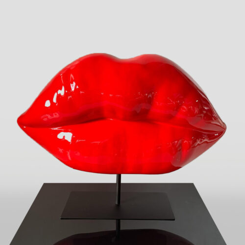 A large, shiny red sculpture of lips mounted on a black stand.