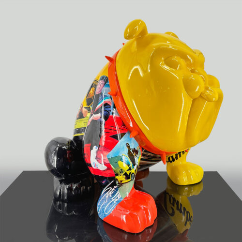 Colorful bulldog sculpture with a yellow face and ears, black and red legs, adorned with various pop culture images and signatures.