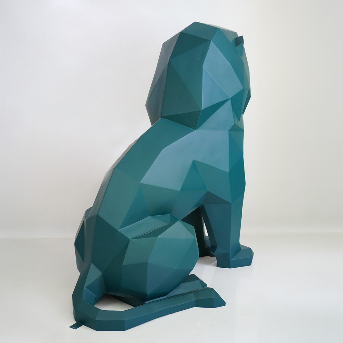 Monochromatic Geometric Lion Figure 2 Geometric teal lion sculpture with faceted surfaces, viewed from the side on a white background.