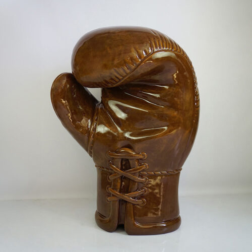 A large ceramic sculpture of a vintage brown boxing glove with detailed lacing and stitching.