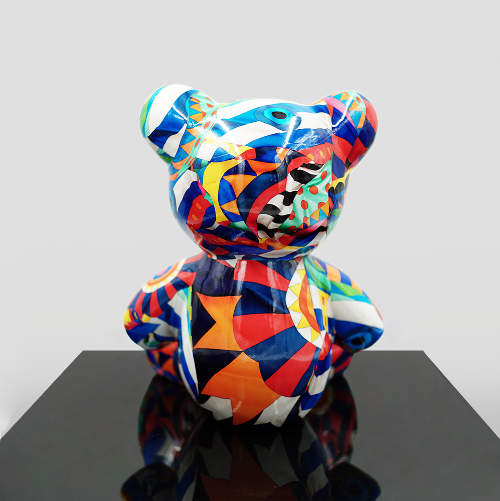 Small Sitting Bear - Mosaic 2 A colorful geometric patterned bear sculpture displayed on a black reflective surface against a plain background.