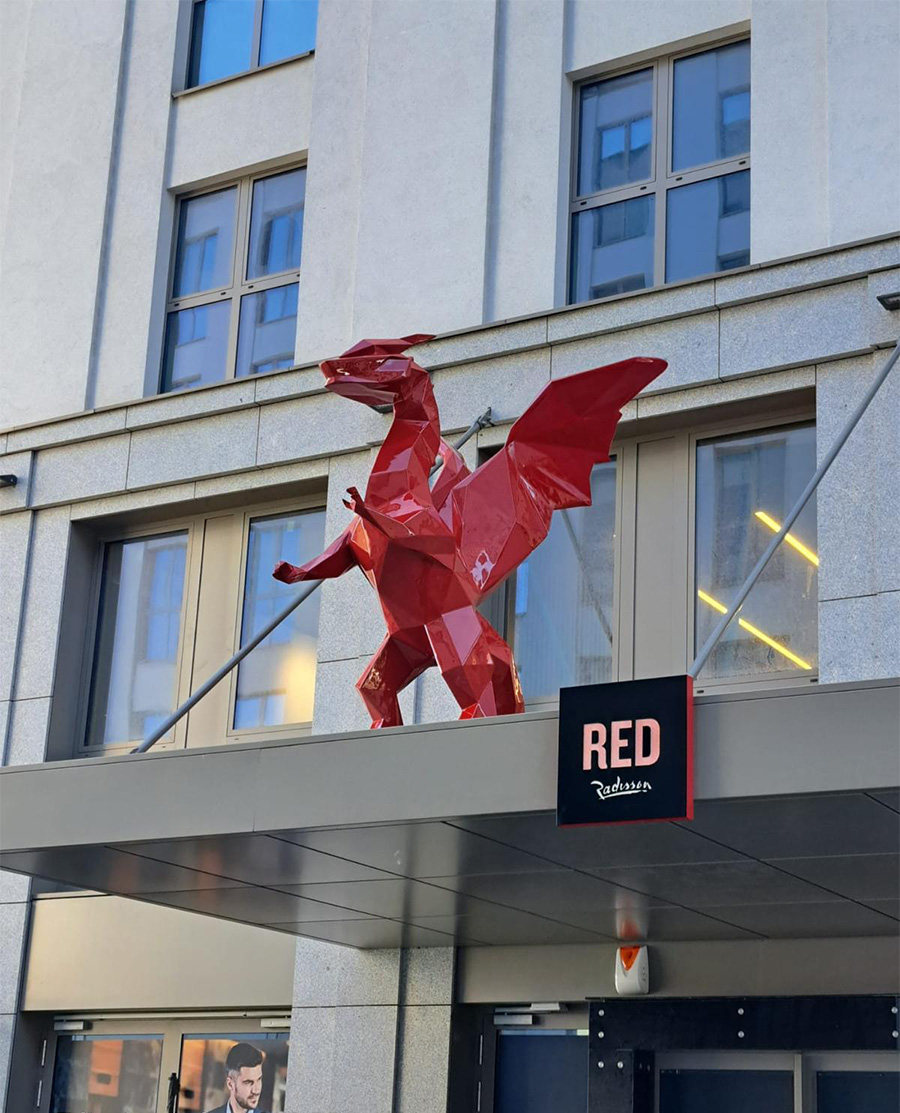 Low Poly Dragons at the Radisson Hotel 7 Czerwona rzeźba smoka przed budynkiem hotelu Radisson RED.