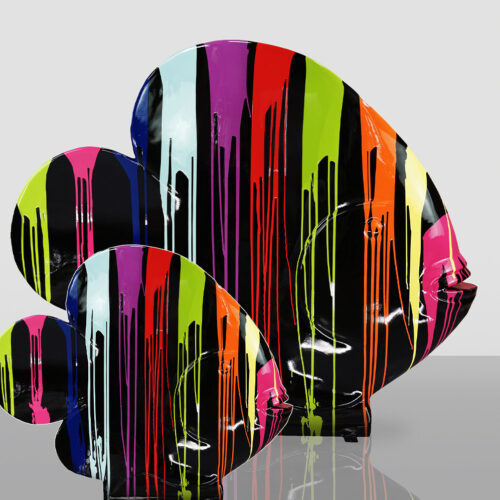 Three brightly colored fish sculptures with vertical drips of paint in black, pink, red, orange, green, blue, and purple against a light gray background.