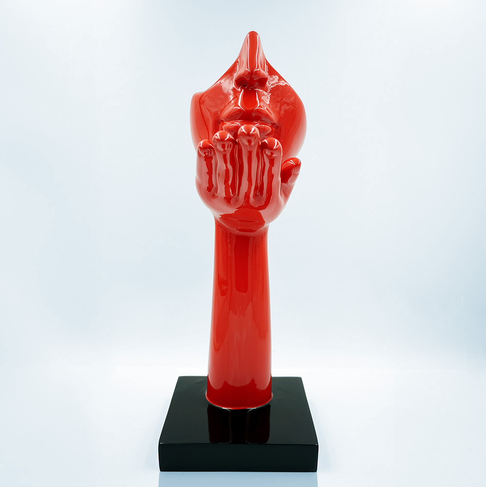 Small Base Mask - Motif I 1 Red sculpture of a hand with an abstract face, mounted on a black square base.