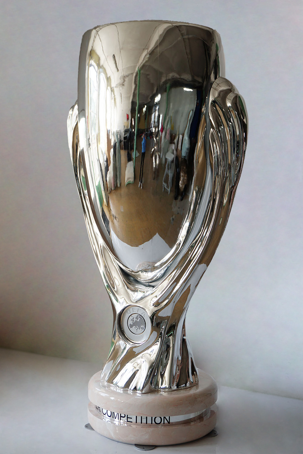 Large UEFA Super Cup Figure for the 2024 Championship 5 Srebrny puchar UEFA Europa Conference League na marmurowej podstawie na białym stole z jasnym tłem.