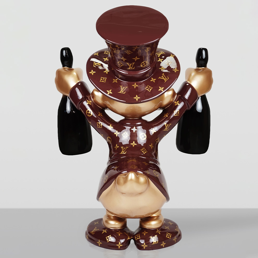 Decorative Figurine – Small Scrooge McDuck 4 Rear view of a shiny brown and gold figurine wearing a patterned top hat and coat holding two black bottles, standing on a reflective surface with a plain light gray background.