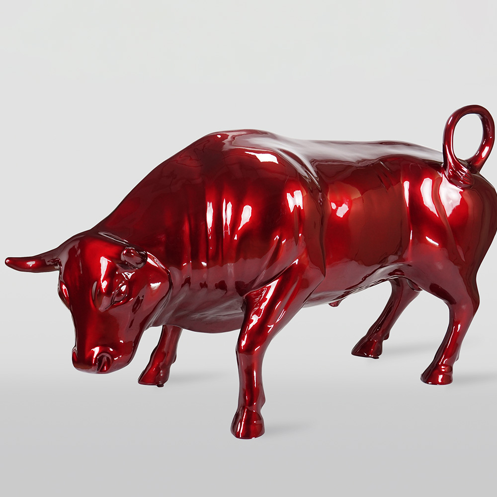 Life-Size Bull - Cherry 2 Glossy red sculpture of a bull with its head lowered and tail curled upwards on a light gray background.
