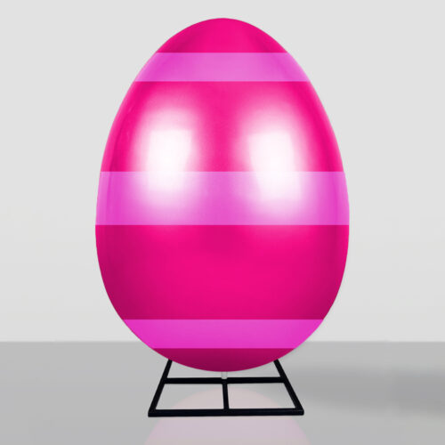 Large shiny pink egg with horizontal lighter pink stripes, standing upright on a black metal stand against a neutral background.