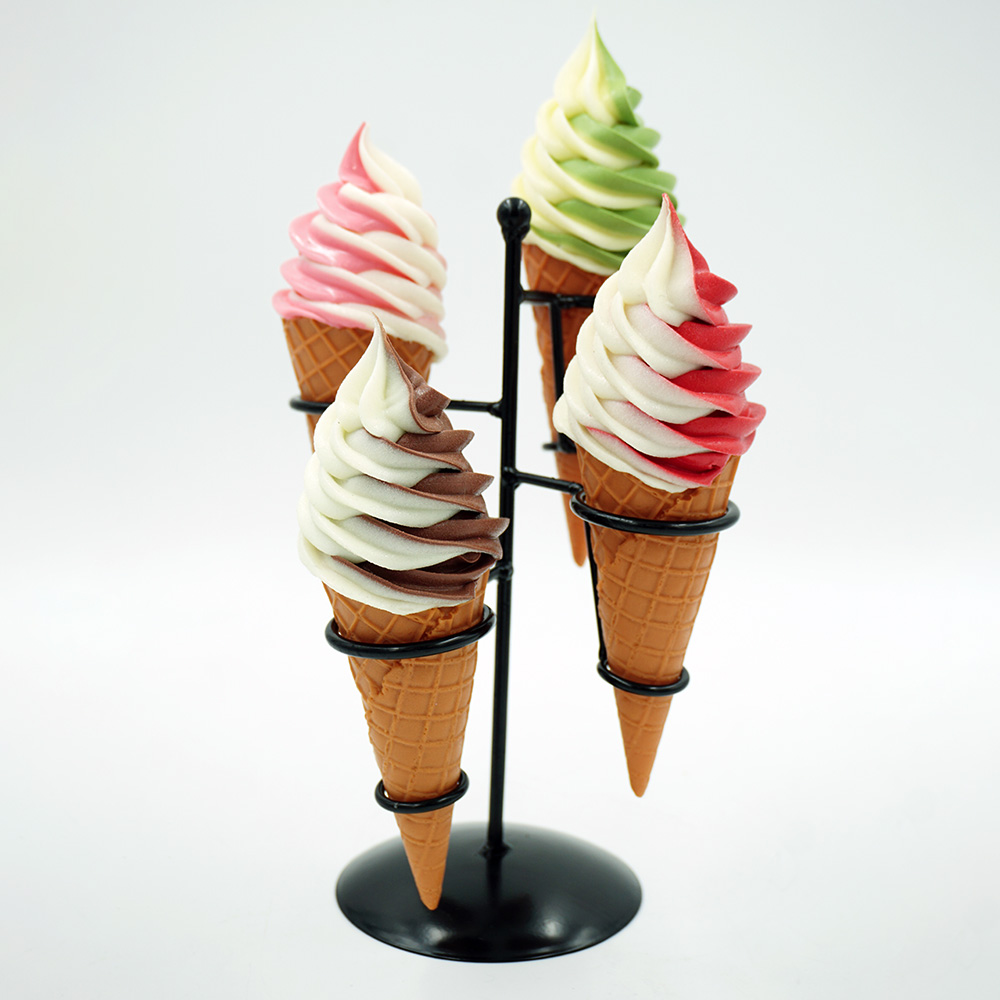 Decorative Ice Cream Basket – Motif III 2 Four soft-serve ice cream cones in a black metal holder, each with swirled flavors: chocolate and vanilla, strawberry and vanilla, green tea and vanilla, and raspberry and vanilla, against a plain white background.