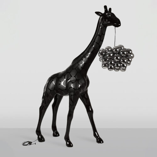 Glossy black giraffe sculpture with a cluster of reflective silver spheres hanging from its mouth against a plain light gray background.