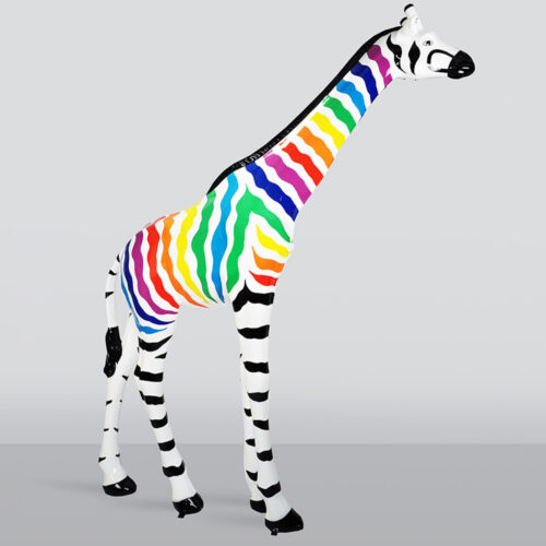 Sculpture of a giraffe with black and white zebra-like stripes on its legs, head, and tail, and rainbow-colored wavy stripes along its body and neck, standing on a light gray surface with a light gray background.