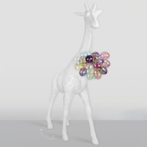 Glossy white giraffe sculpture with a necklace made of translucent, colorful, inflated balloon-like spheres around its neck, standing against a plain light gray background