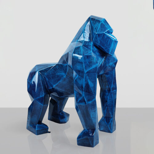 Glossy blue geometric sculpture of a gorilla standing on a reflective surface against a plain white background