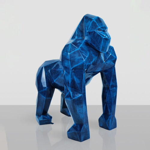 Geometric blue sculpture of a gorilla standing on all fours against a light gray background with a reflective surface.