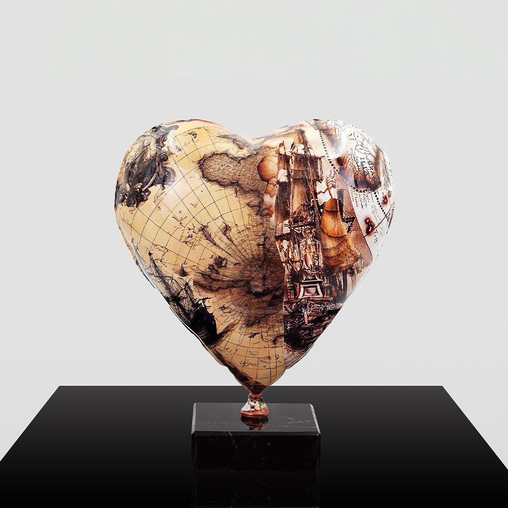 Decorative Heart-Shaped Balloon Figurine 14 Heart-shaped sculpture with vintage nautical map and ship illustrations mounted on a black square base against a plain gray background