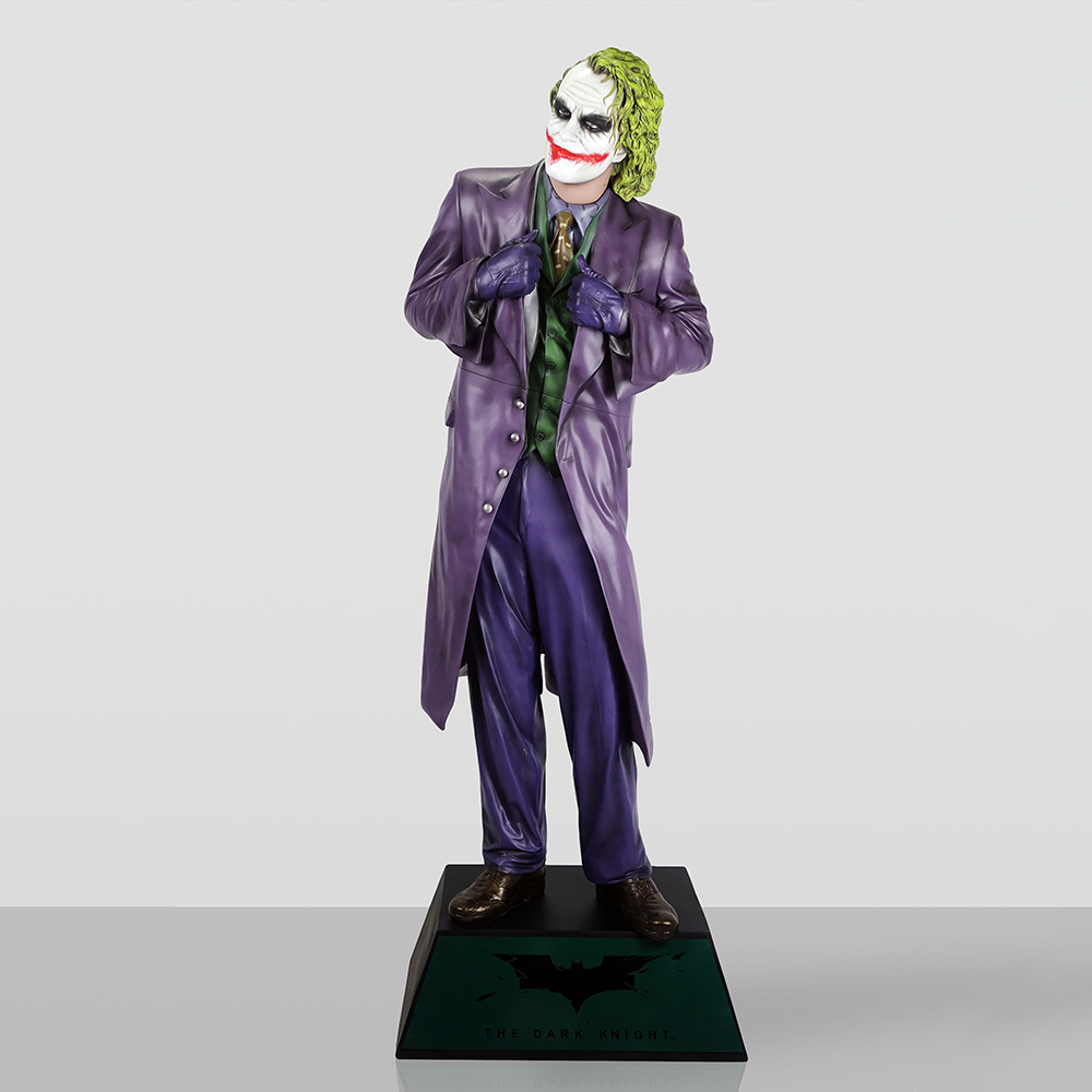 Decorative Figure – Joker 3 A detailed figurine of the Joker from The Dark Knight, wearing a purple suit, green vest, purple gloves, and brown shoes, standing on a black base with The Dark Knight logo and text.