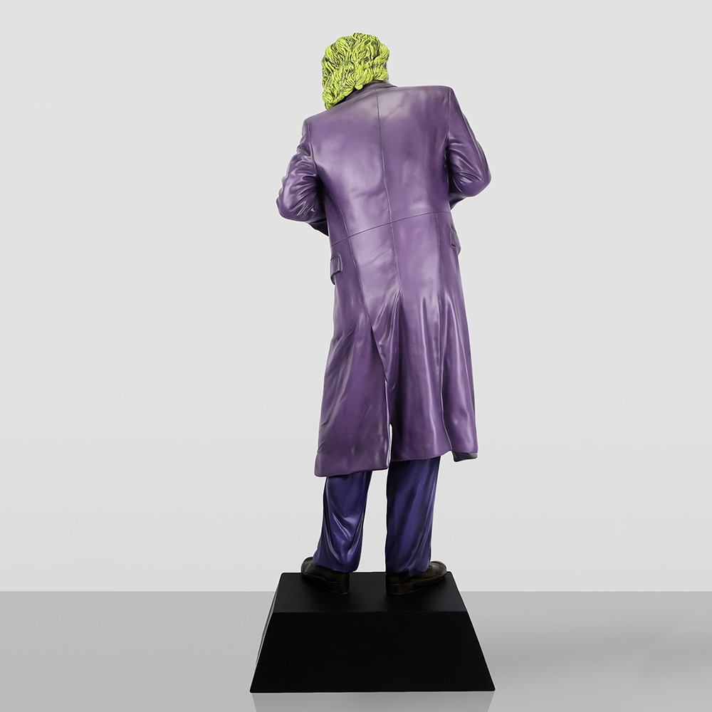 Decorative Figure – Joker 4 Rear view of a figurine wearing a purple long coat and matching pants, standing on a black pedestal, with bright yellow-green hair.