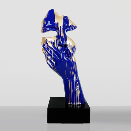 Abstract blue and gold sculpture of a hand covering a stylized face, mounted on a black rectangular base against a plain light gray background
