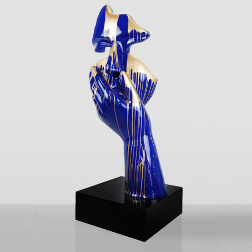 Glossy blue and gold abstract sculpture of a hand holding an abstract bird-like shape, mounted on a black rectangular base with a reflective surface.