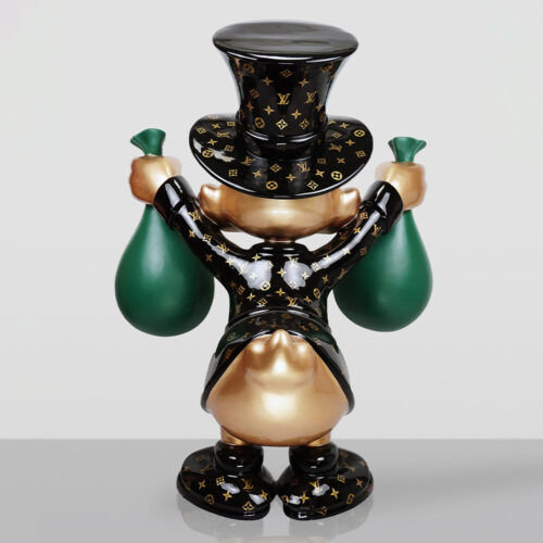 Golden chipmunk statue wearing a black Louis Vuitton patterned top hat, coat, and shoes, holding two green money bags, viewed from behind on a reflective surface with a plain background.