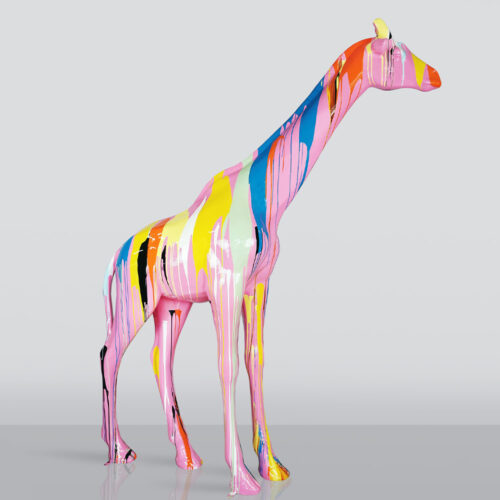 Sculpture of a giraffe covered in glossy multicolored paint drips including pink, yellow, blue, orange, and black, standing on a reflective surface against a plain gray background
