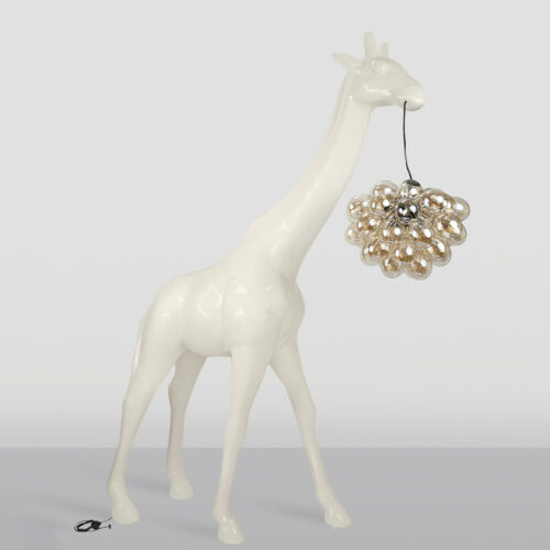 Glossy white giraffe sculpture holding a cluster of shiny, reflective silver spheres by a wire in its mouth, standing on a gray surface against a light gray background