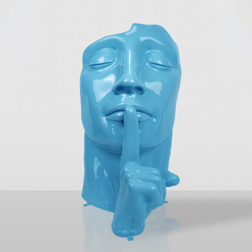 Glossy blue sculpture of a serene human face with closed eyes and a hand with index finger raised to lips in a shushing gesture, placed on a reflective surface against a plain light grey background.