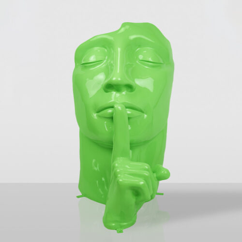 Glossy lime green sculpture of a human face with closed eyes and a hand with the index finger pressed against the lips in a shushing gesture, set against a plain light gray background with a reflective surface.