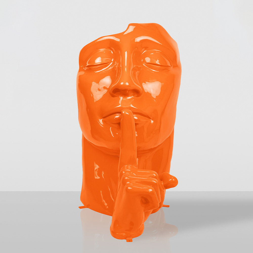 Orange Glossy orange sculpture of a face with eyes closed and a finger held up to the lips in a shushing gesture, set against a plain gray background.