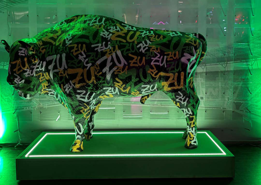 Sculpture of a cow covered in graffiti-style text 